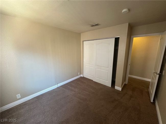 Unfurnished bedroom with baseboards, visible vents, dark carpet, and a closet | Image 14