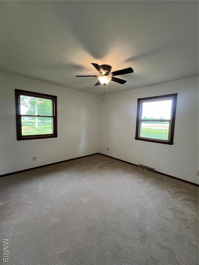 Empty room featuring a ceiling fan, a wealth of natural light, baseboards, and carpet | Image 9