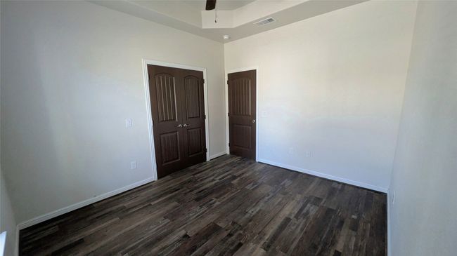 Spare room with a raised ceiling, visible vents, dark wood-type flooring, a ceiling fan, and baseboards | Image 4
