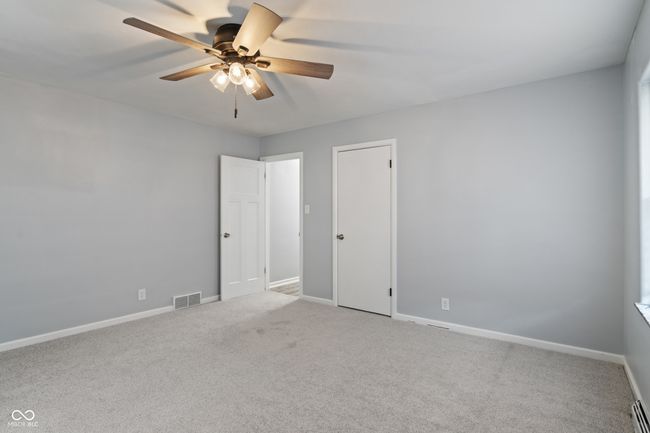 unfurnished bedroom featuring light carpet, baseboards, baseboard heating, and ceiling fan | Image 31