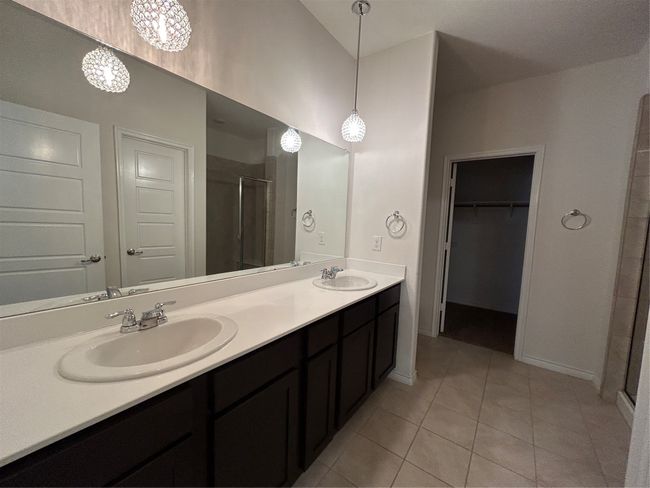 Full bathroom featuring a stall shower, double vanity, tile patterned flooring, a spacious closet, and baseboards | Image 27