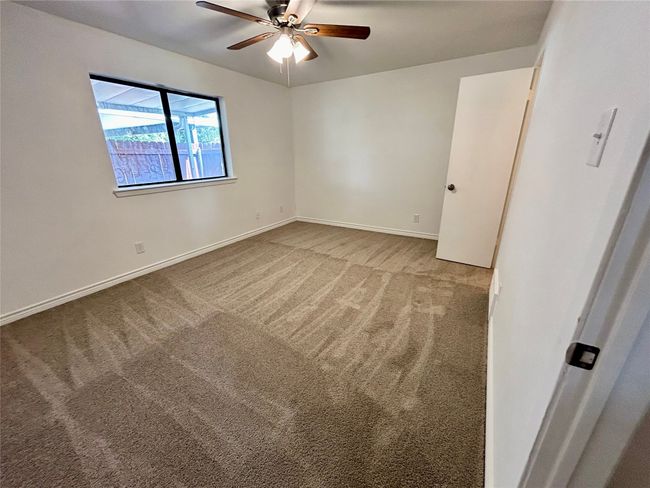 Unfurnished bedroom featuring carpet flooring, baseboards, and ceiling fan | Image 13