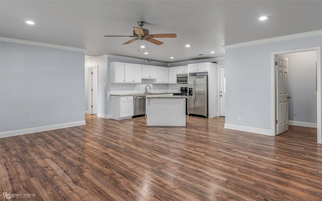 Kitchen with stainless steel appliances, dark wood-style flooring, baseboards, a ceiling fan, and crown molding | Image 7