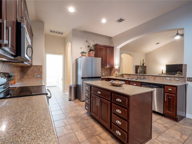 Kitchen featuring appliances with stainless steel finishes, arched walkways, a center island, tasteful backsplash, and recessed lighting | Image 8