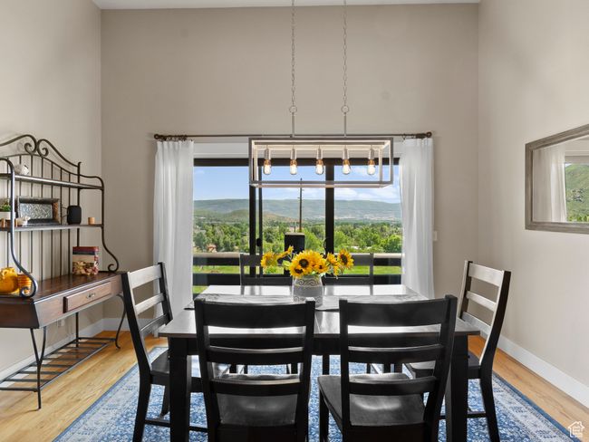 Separate dining space featuring a high ceiling, hardwood floors, sliding glass doors leading out to the deck with panoramic views. | Image 5