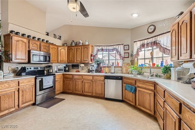 Kitchen featuring brown cabinetry, stainless steel appliances, a sink, and light countertops | Image 11