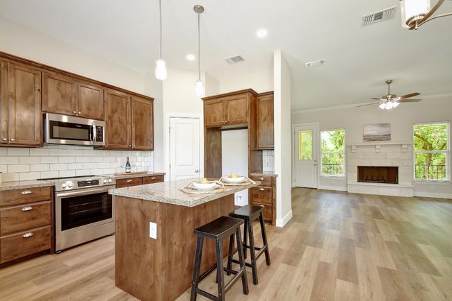 Kitchen featuring stainless steel appliances, backsplash, light wood-style flooring, light stone countertops, and ornamental molding | Image 10