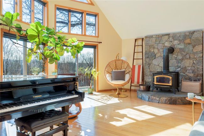 Living area featuring high vaulted ceiling, baseboards, a wood stove, and wood finished floors | Image 16
