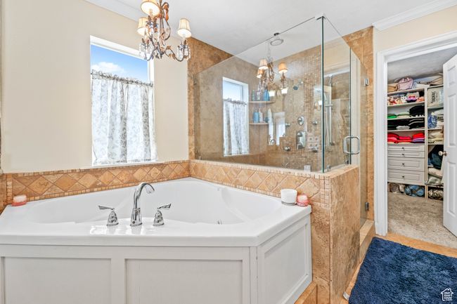 Full bathroom featuring a notable chandelier, ornamental molding, a bath, a stall shower, and a walk in closet | Image 27
