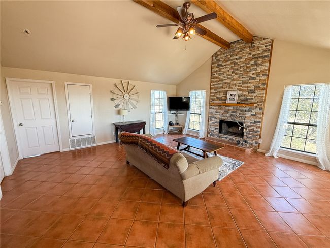 Living area with tile patterned floors, high vaulted ceiling, beam ceiling, a ceiling fan, and visible vents | Image 10