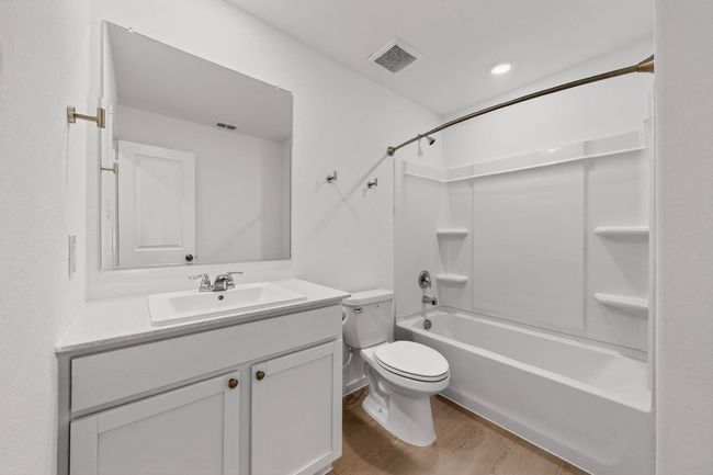 Bathroom featuring bathtub / shower combination, toilet, vanity, and wood finished floors | Image 13