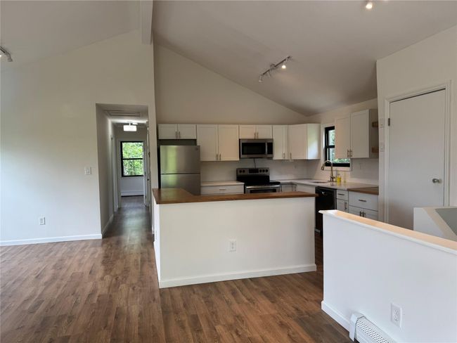 Kitchen featuring stainless steel appliances, high vaulted ceiling, rail lighting, dark wood finished floors, and white cabinets | Image 4