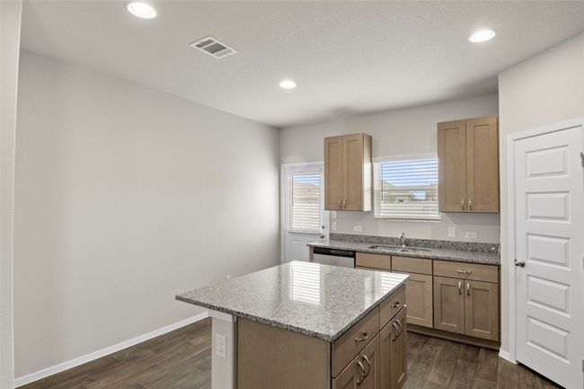 Kitchen with dishwasher, dark wood-style flooring, visible vents, a sink, and a kitchen island | Image 16
