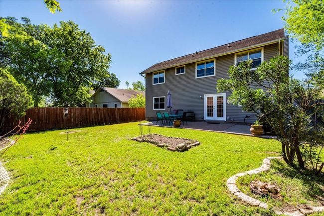 Rear view of house featuring French doors, a patio area, fence, and a yard. | Image 25