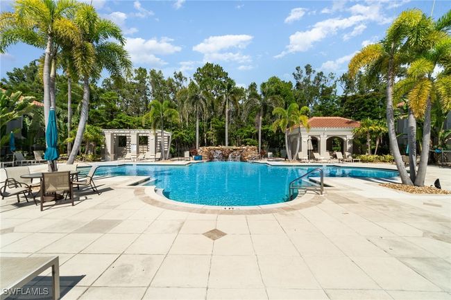 Community pool with a patio area and view of scattered trees | Image 19