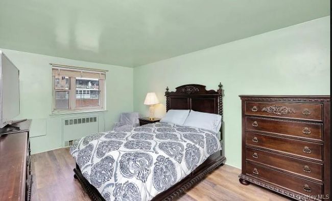 Bedroom with light wood-style flooring and radiator heating unit | Image 10