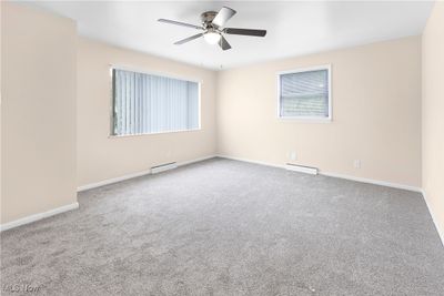 Unfurnished room featuring a baseboard radiator, ceiling fan, and carpet flooring | Image 3