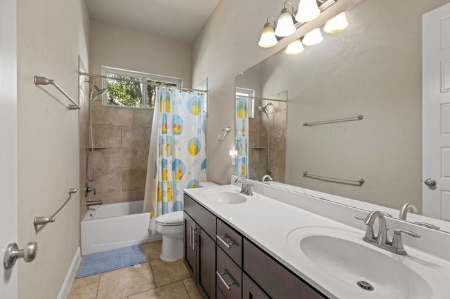 Full bathroom with shower / tub combo with curtain, double vanity, and tile patterned floors | Image 16