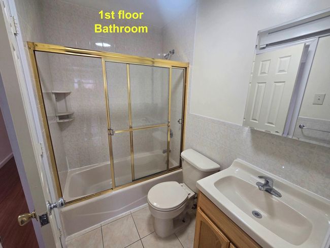 Bathroom featuring toilet, combined bath / shower with glass door, vanity, tile walls, and tile patterned flooring | Image 10