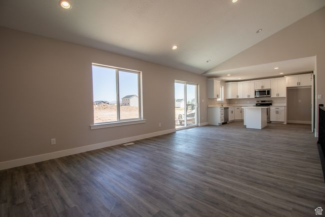 Unfurnished living room with recessed lighting, lofted ceiling, dark wood-style floors, and baseboards. *Photo in picture is similar to the home being built | Image 5