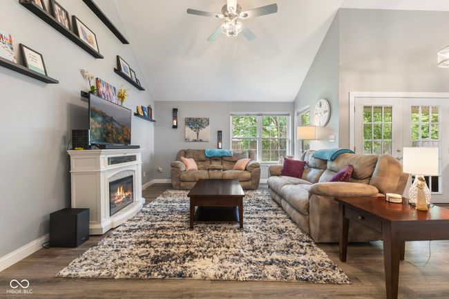 living room featuring ceiling fan, wood finished floors, high vaulted ceiling, and a glass covered fireplace | Image 4