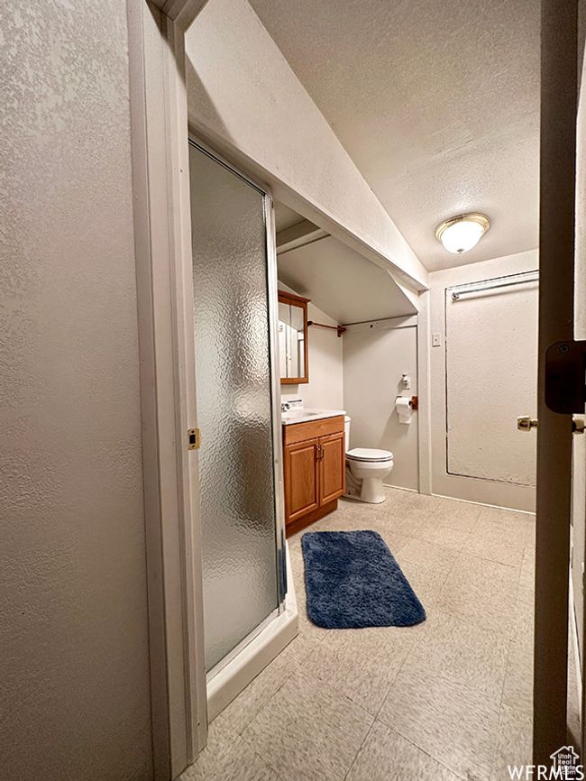 Bathroom featuring vanity, vaulted ceiling, a textured wall, a textured ceiling, and a stall shower | Image 28