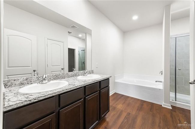 Bathroom with a shower stall, a garden tub, double vanity, wood finished floors, and recessed lighting | Image 13