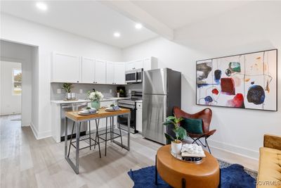 Kitchen with white cabinets, decorative backsplash, beam ceiling, appliances with stainless steel finishes, and light hardwood / wood-style floors | Image 2