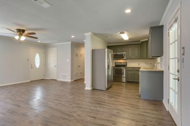 Kitchen featuring appliances with stainless steel finishes, ornamental molding, dark wood finished floors, ceiling fan, and a textured ceiling | Image 11