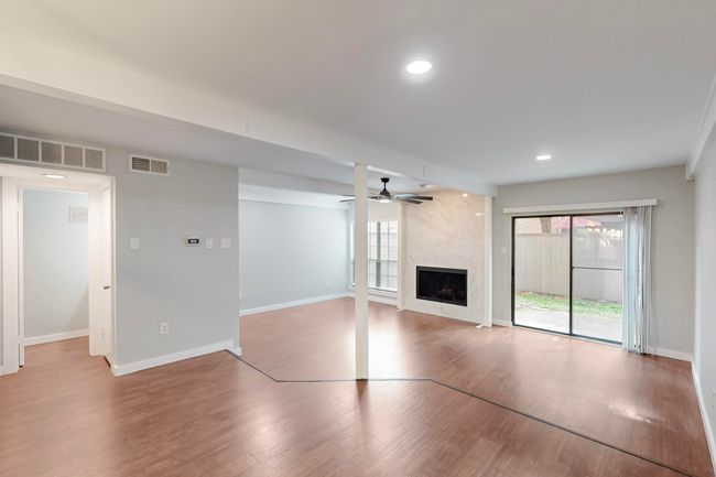 Unfurnished living room with a premium fireplace, a ceiling fan, visible vents, baseboards, and wood finished floors | Image 8