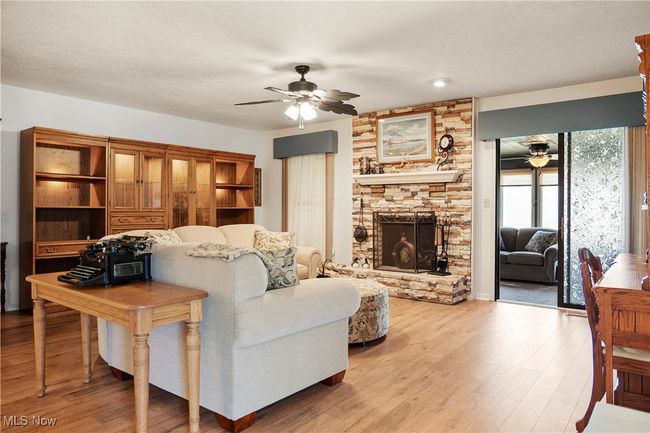 Living area featuring ceiling fan, light wood finished floors, and a fireplace | Image 7