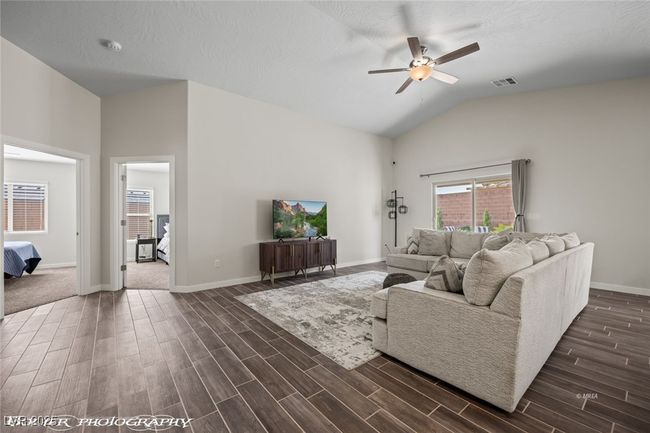 Living room with lofted ceiling, ceiling fan, dark wood-style floors, and baseboards | Image 19