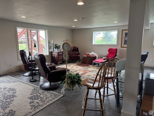 Basement living room with concrete floors, a textured ceiling, recessed lighting, and baseboards | Image 16