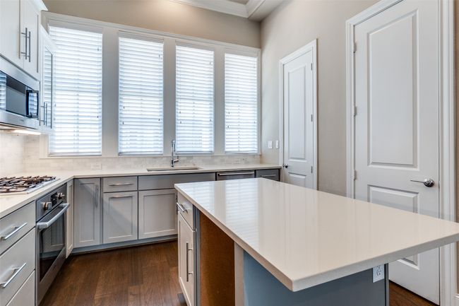 Kitchen with appliances with stainless steel finishes, gray cabinetry, dark wood-type flooring, crown molding, and light countertops | Image 19