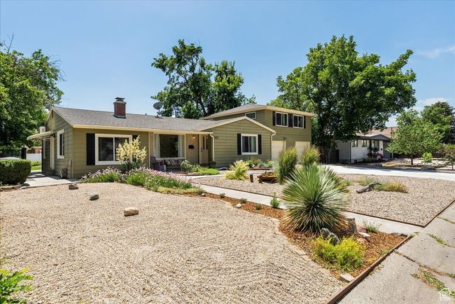 View of front of house with an attached garage, a chimney, and driveway | Image 7