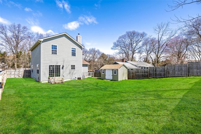 Rear view of house with a fenced backyard, a storage unit, a yard, and an outbuilding | Image 28