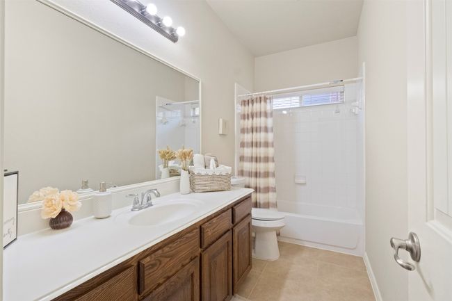 Full bathroom featuring vanity, toilet, tile patterned flooring, shower / bath combo, and baseboards | Image 18
