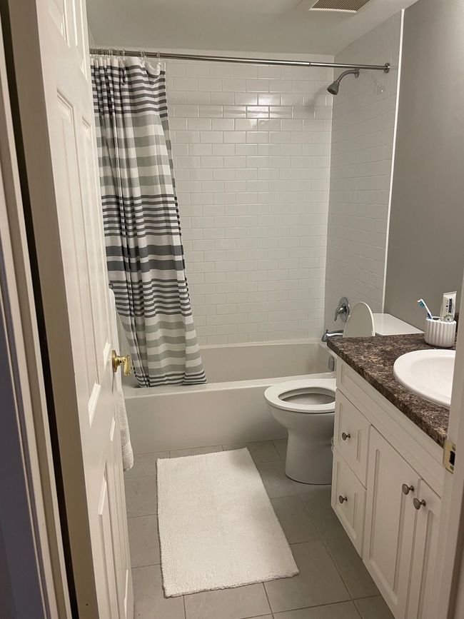 Bathroom with toilet, tile patterned flooring, vanity, and shower / bath combo with shower curtain | Image 18