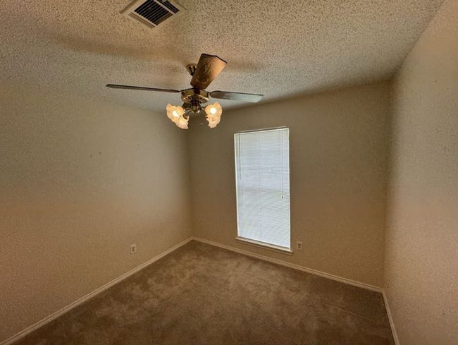 Empty room with a textured ceiling, ceiling fan, and carpet floors | Image 21
