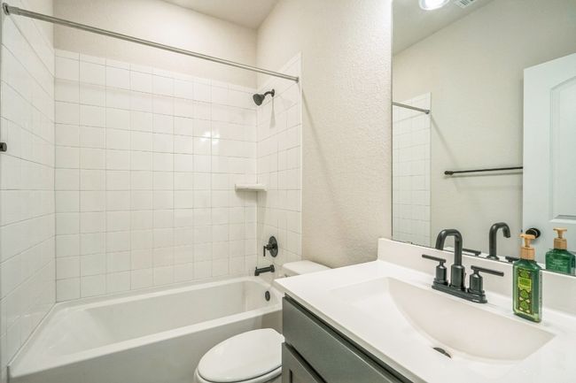 Bathroom featuring toilet, vanity, shower / washtub combination, and a textured wall | Image 9