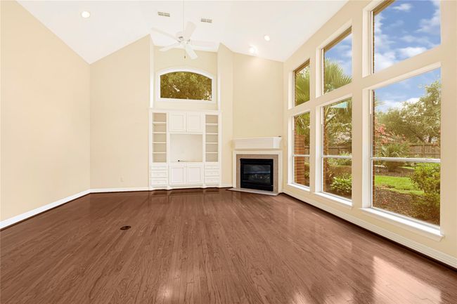 Spacious family room featuring elegant custom built-ins, a cozy fireplace, and abundant natural light from expansive windows. | Image 22