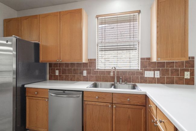 Kitchen with appliances with stainless steel finishes, a sink, and light countertops | Image 18