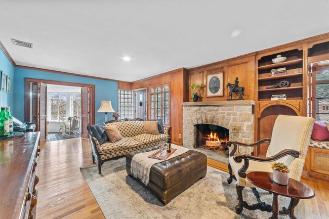 Living area with wooden walls, wood finished floors, a fireplace, and crown molding | Image 8