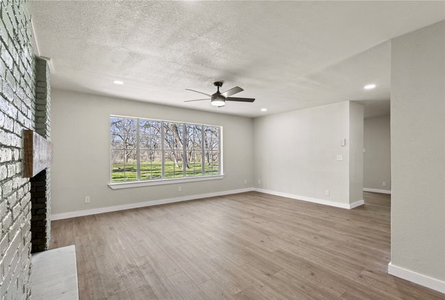 Unfurnished living room with baseboards, a fireplace, a textured ceiling, and light wood finished floors | Image 7