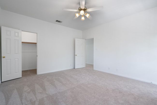 Unfurnished bedroom featuring light colored carpet, baseboards, a walk in closet, and visible vents | Image 33
