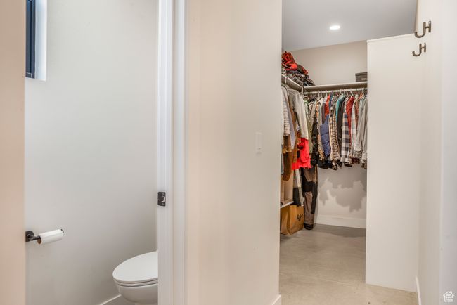 Bathroom with concrete flooring, a spacious closet, recessed lighting, toilet, and baseboards | Image 31