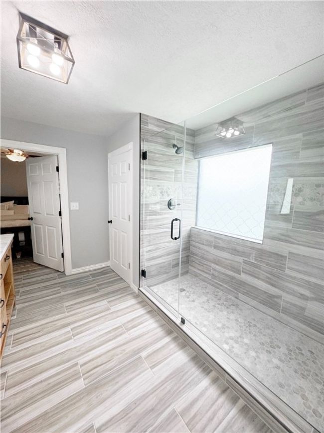 Full bathroom featuring wood finish floors, vanity, baseboards, a textured ceiling, and a stall shower | Image 4