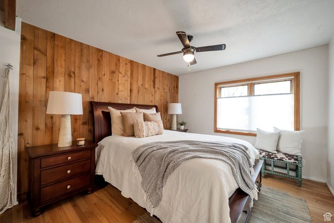 Bedroom with wood walls, wood finished floors, and a ceiling fan | Image 14