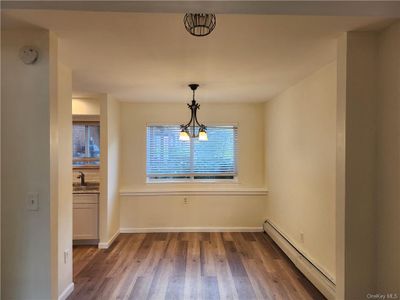 Unfurnished dining area with wood-type flooring, a baseboard radiator, an inviting chandelier, and a wealth of natural light | Image 3