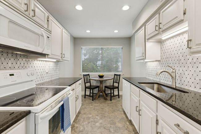 Kitchen featuring white appliances, a sink, decorative backsplash, white cabinets, and recessed lighting | Image 12